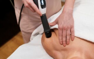 Chiropractor applying shockwave therapy to a patient's shoulder for pain relief at Whitefish Chiropractic